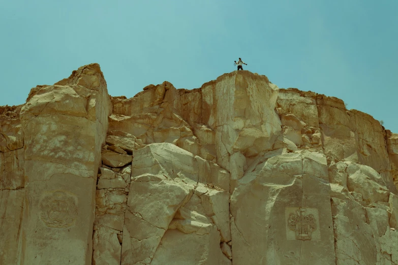 two people stand on top of a mountain above some rock formations