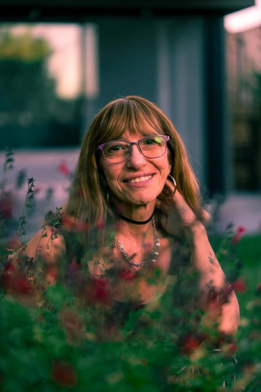 woman in glasses looking to the side with plants around her