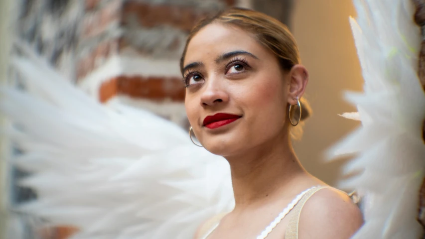 a young woman in white dress holding white wings