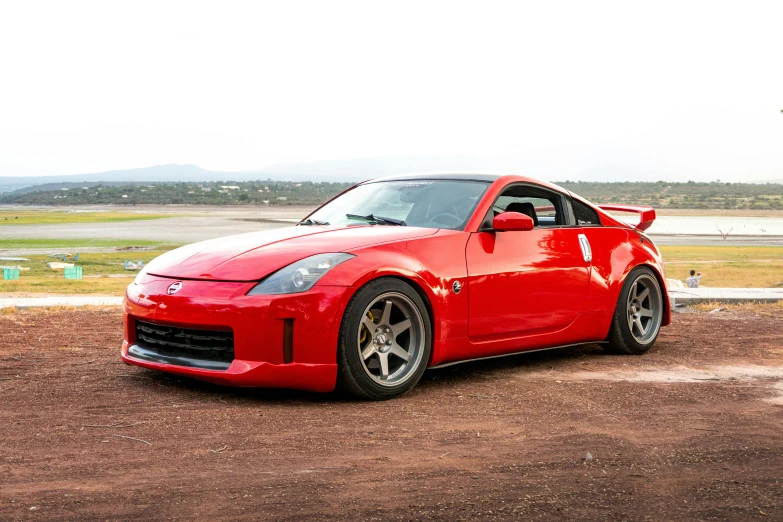 a red car driving down a dirt road