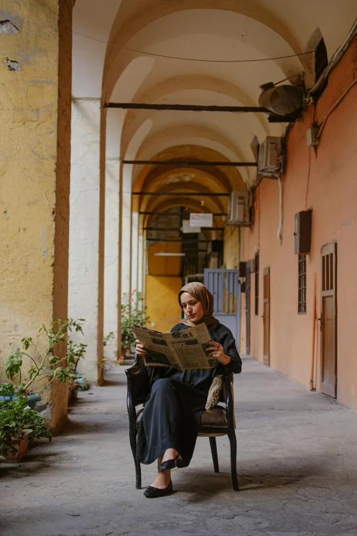 a woman sitting in a chair and working on a large piece of paper