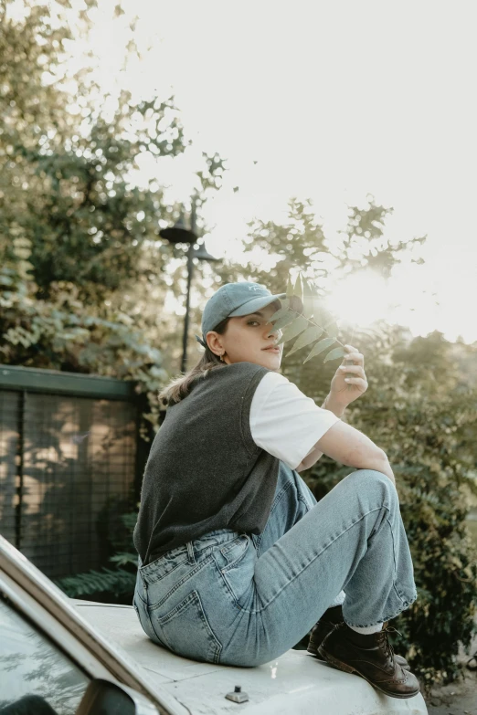 young man sitting on the roof of his car looking off into the distance