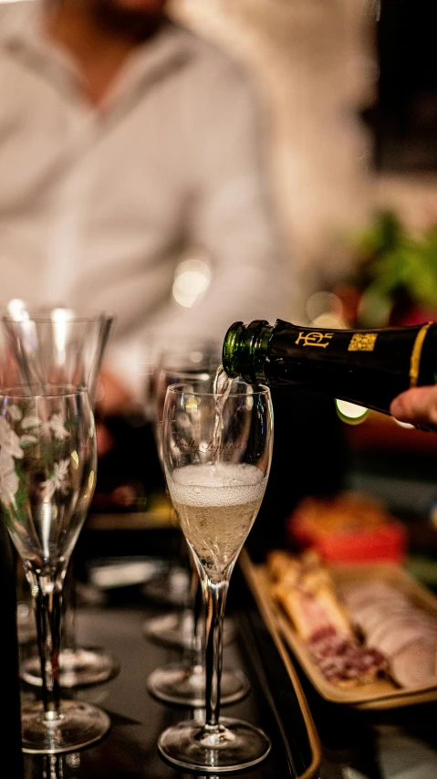 two glasses are being filled with liquid by a bottle