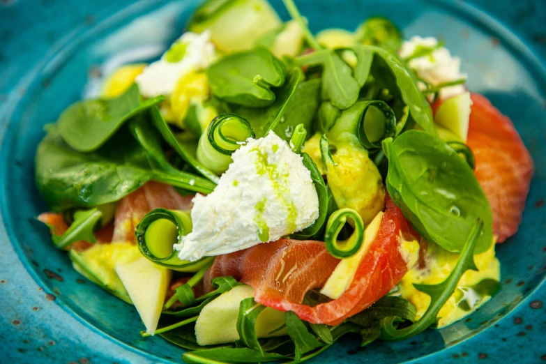 a blue bowl filled with veggies and cheese