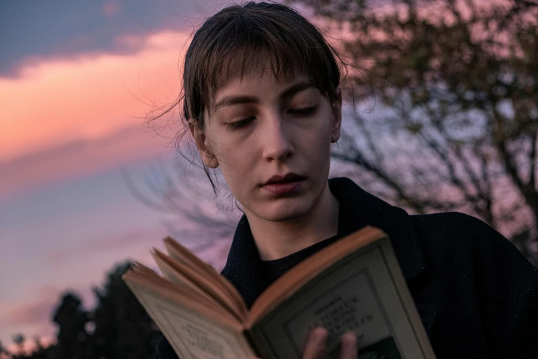 a person is reading a book outside and has closed eyes