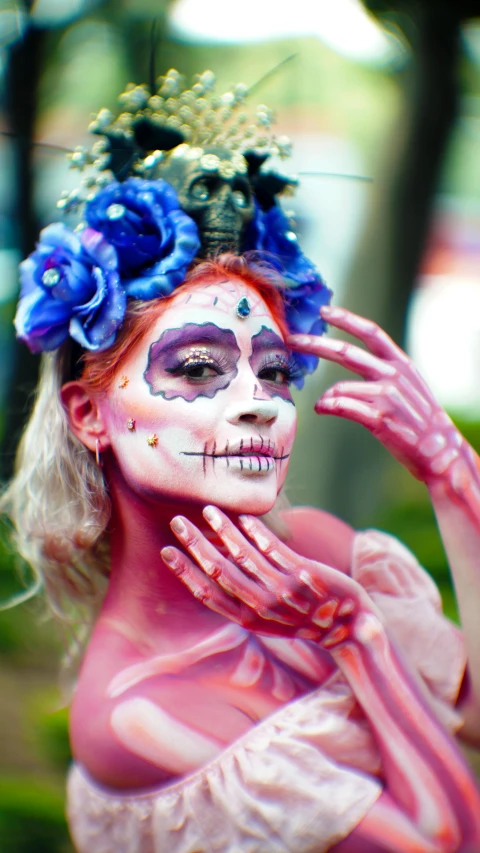 a woman in makeup has blue flowers on her head