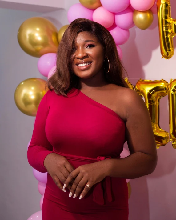 a woman in pink dress posing in front of balloons