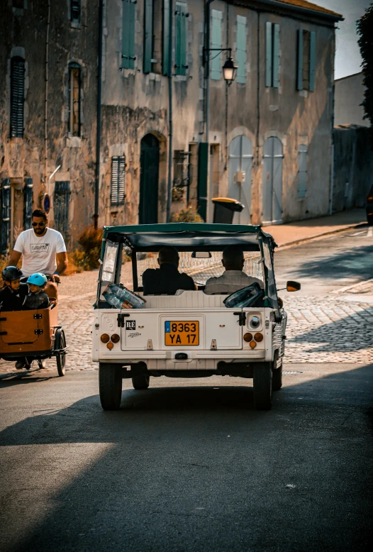 a white small truck traveling down a street past buildings