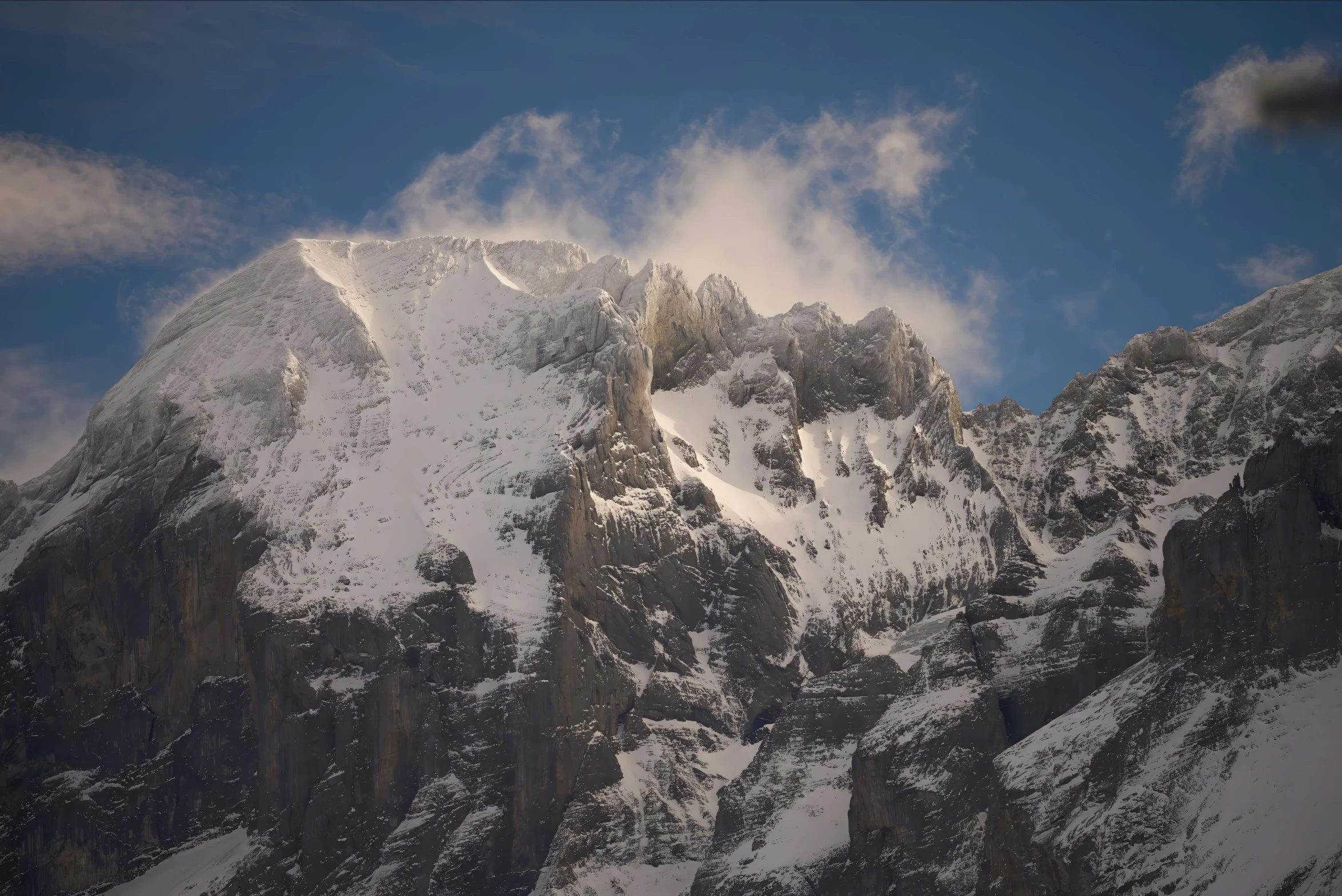 a snow covered mountain range covered in thick clouds