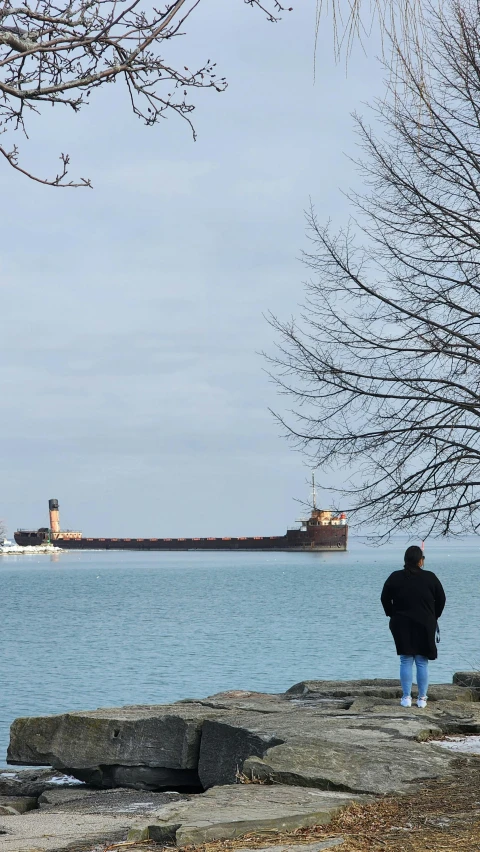 a person in a black jacket standing by the water