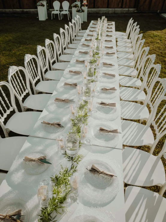 a white outdoor table setting with white folding chairs