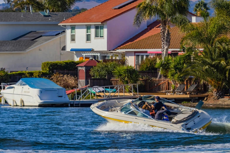 a speed boat speeds along the water by a house