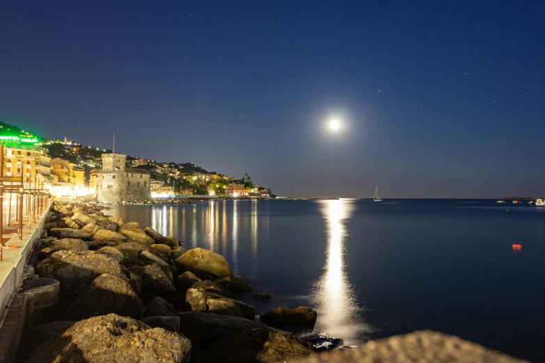 full moon and water at night in front of a castle with a green dome