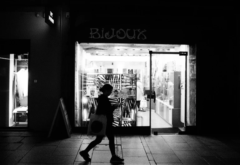 a woman in black walking down the sidewalk