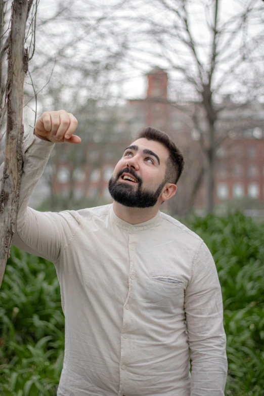 a man wearing a white outfit standing in front of a tree