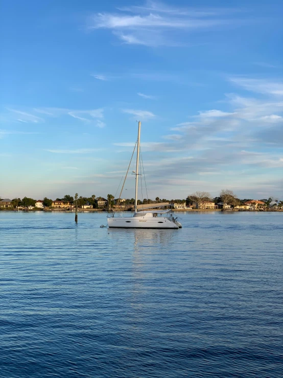 a sailboat sitting on top of a lake next to shore