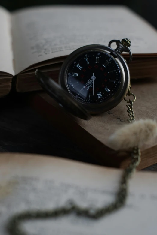 an open book with a watch on it sitting next to a chain