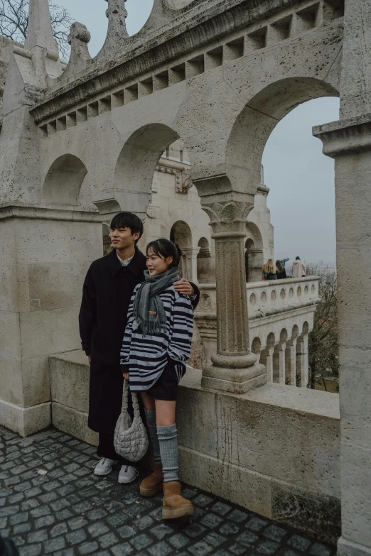 two people standing on the side of an ancient building