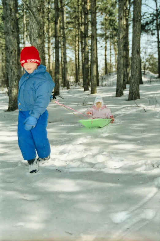 a young person with a child in the snow with sled