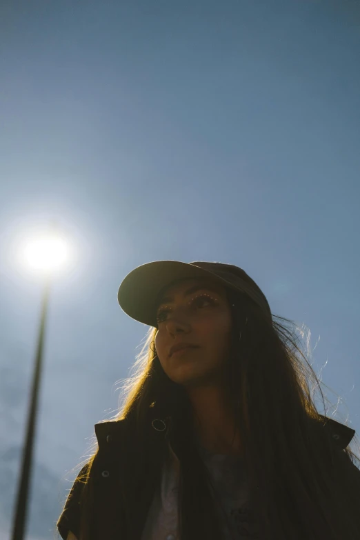 a girl looking at the sky wearing a hat and jacket