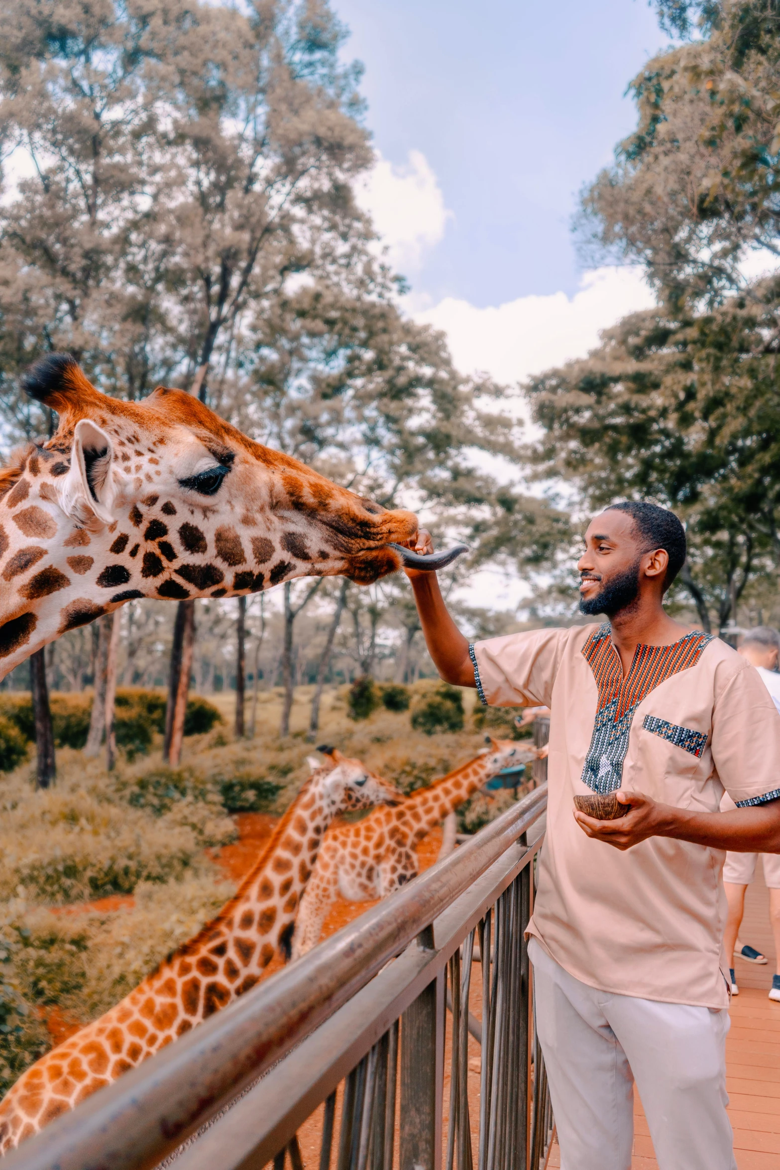 a man petting a giraffe on top of a wooden fence