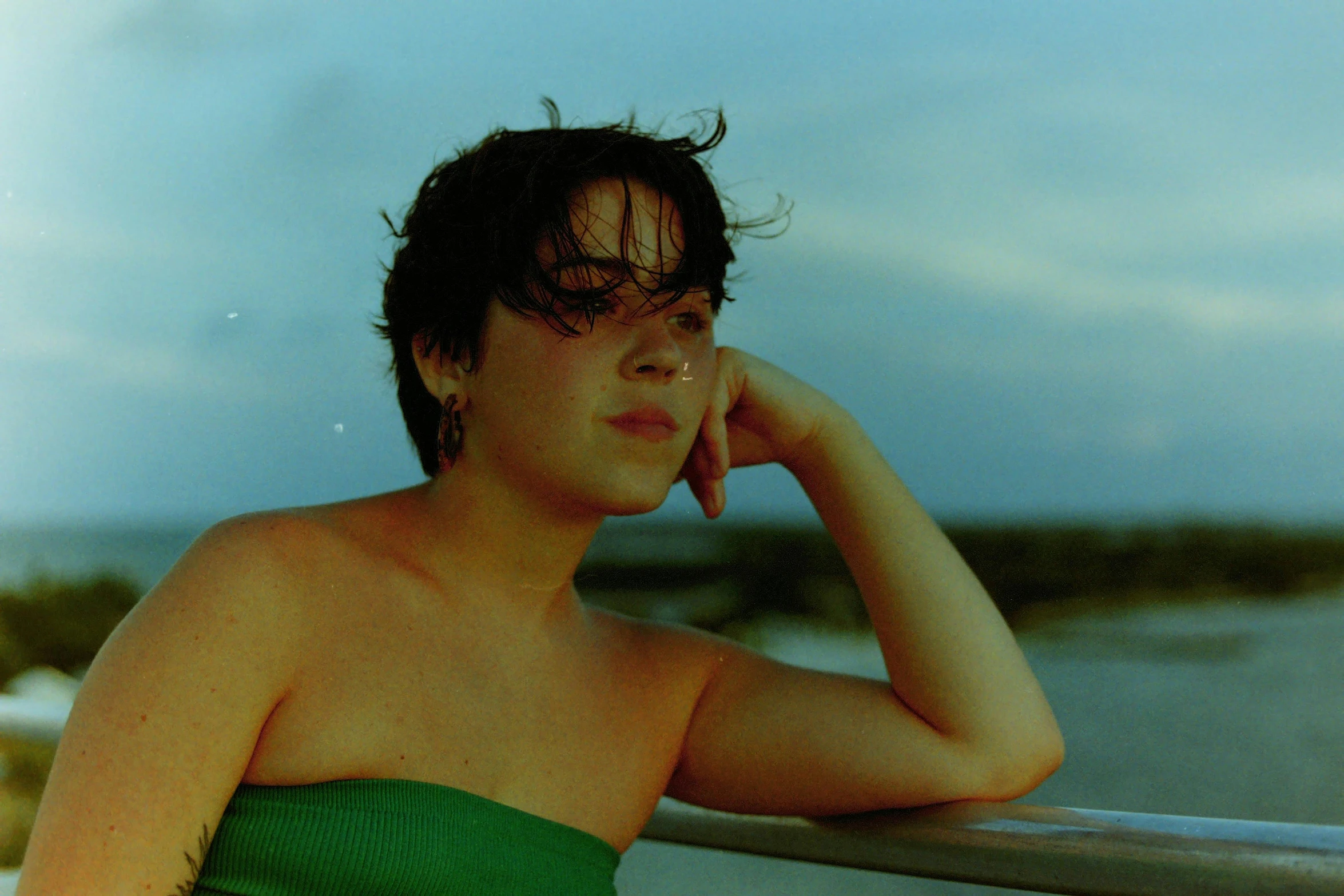 a girl that is leaning on a rail looking in the distance