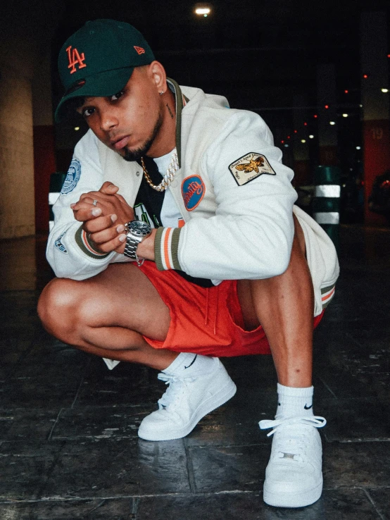 man with white jacket and orange shorts crouching on the floor