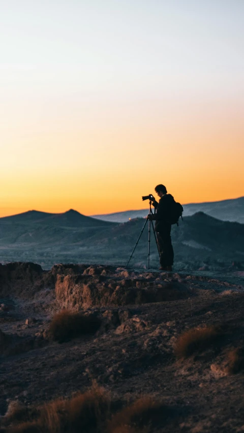 a man standing on a rocky hillside with a camera