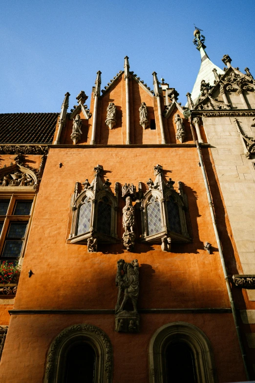 the side of a red building with multiple windows and a statue above it