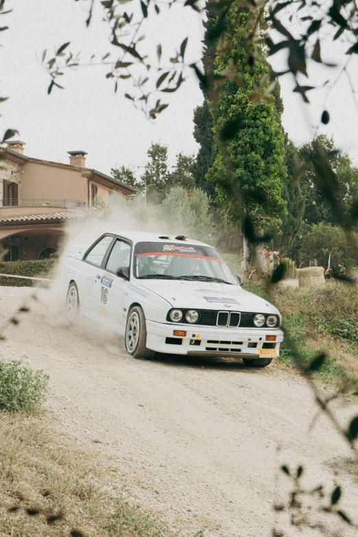 an automobile on a dirt road driving towards a house