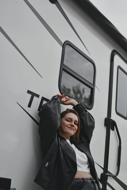 woman in jacket leaning on rv and smiling