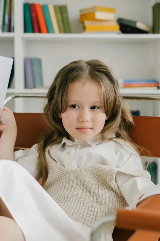 the little girl is smiling while holding her papers