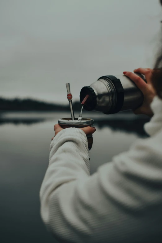 a woman holding a bottle with a screwdriver and a lighter