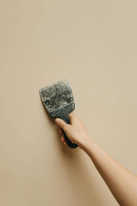 hand holding a gray cloth in the corner of the room