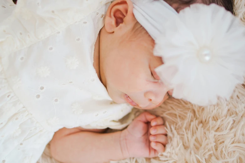 a baby is sleeping on a furry rug and the head of a flower in it's hands