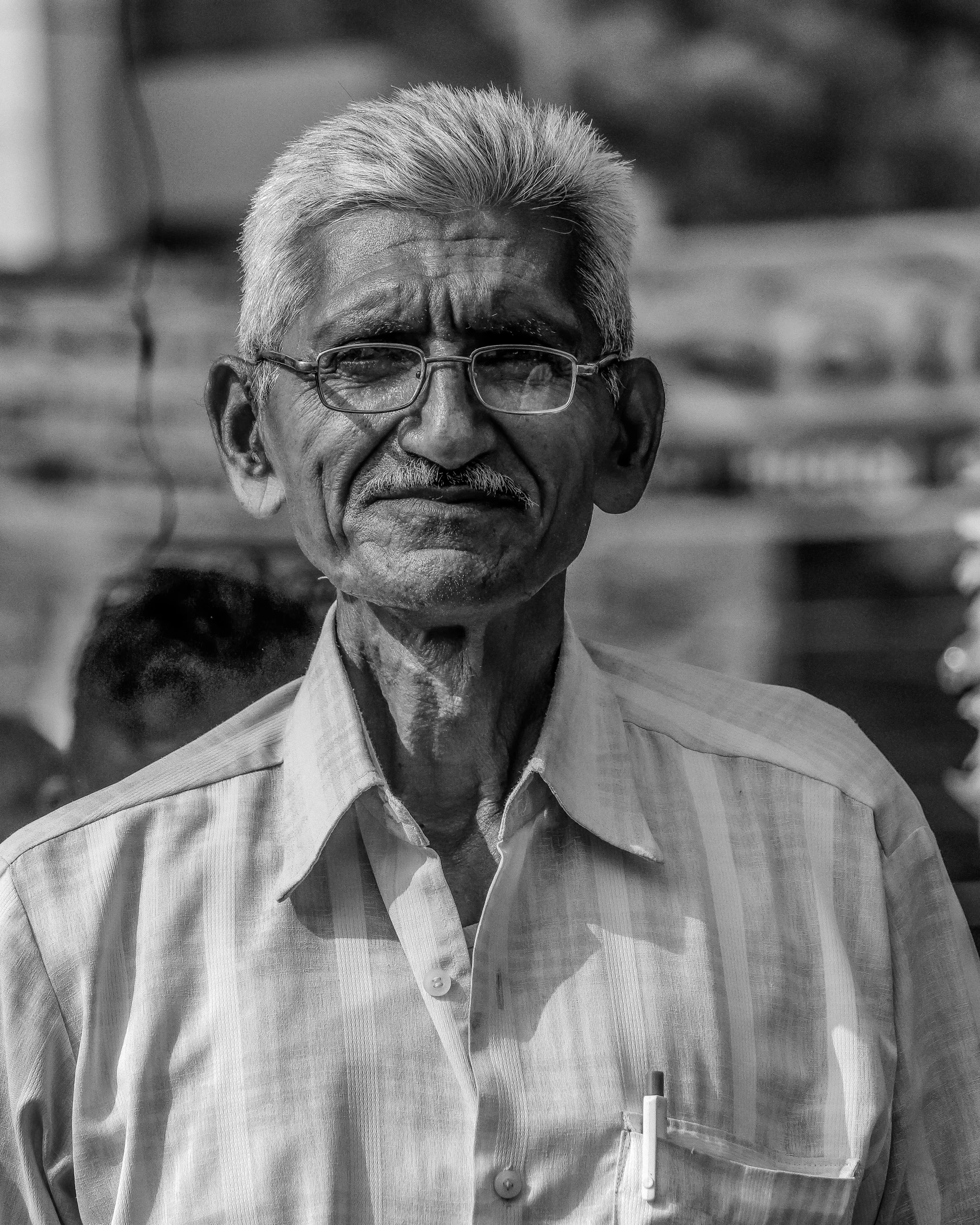 an old man standing outside looking into the camera