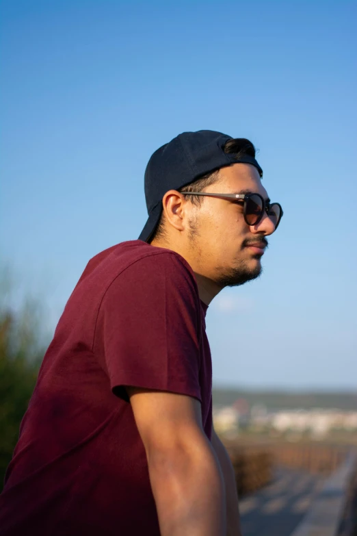 a man wearing sunglasses and a baseball cap, looking down