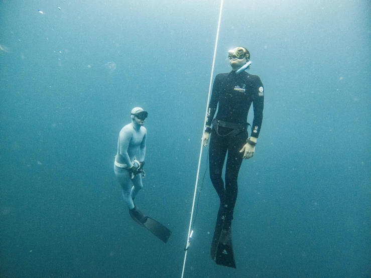 a man in wet suit standing next to another male under water