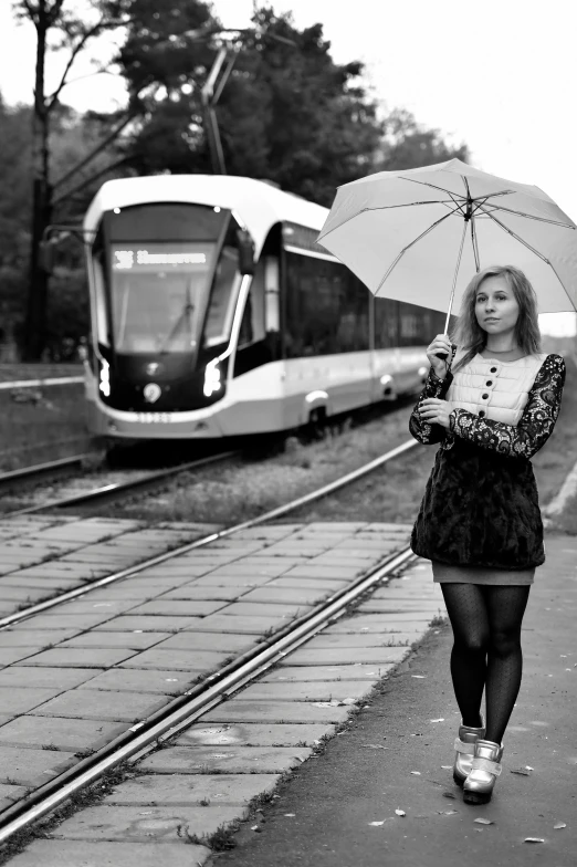 the young lady has an umbrella while she walks on the sidewalk