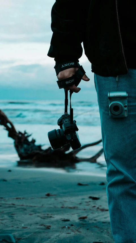 a person holding a camera and looking at the water