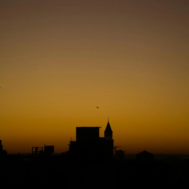 a city skyline with a silhouette of an airplane flying over the building