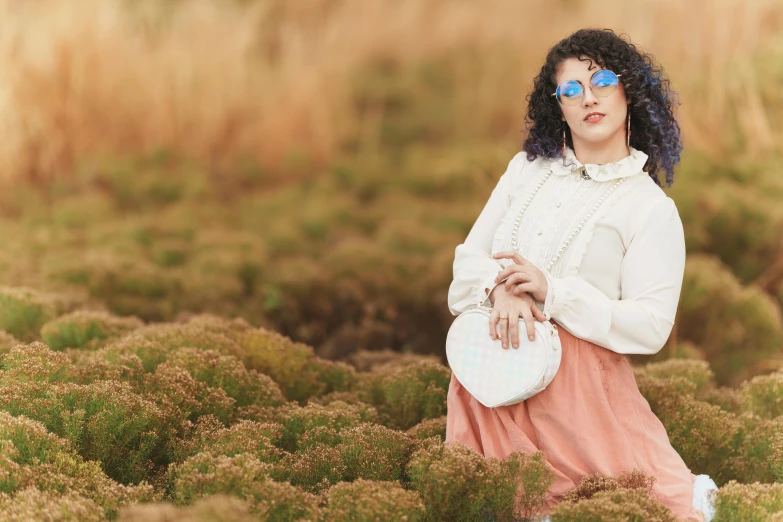 a woman in white sweater and blue glasses in grass field