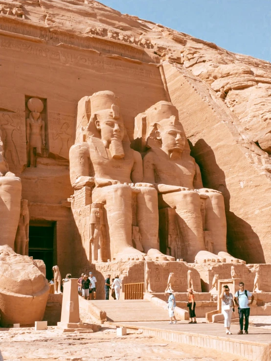 three large statues and a staircase inside of a large building