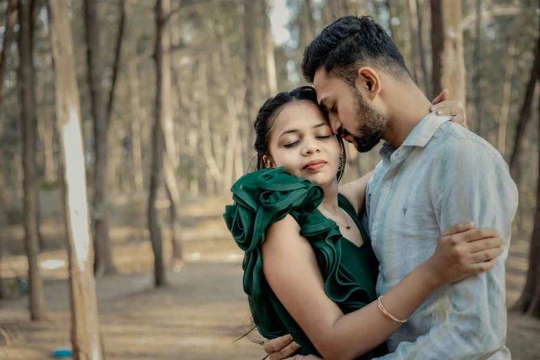 a woman hugging another man in the middle of the forest