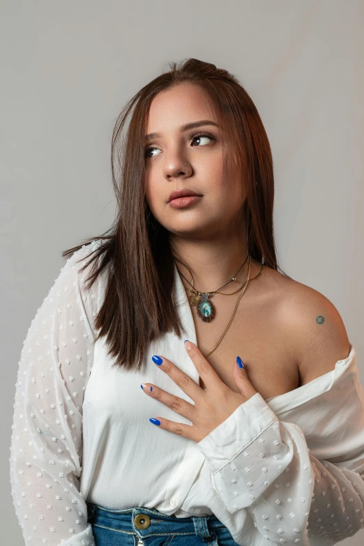 a woman wearing blue fingernails and jeans is looking into the distance