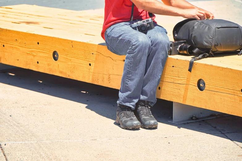 a young man sits on a wooden bench and poses for the camera