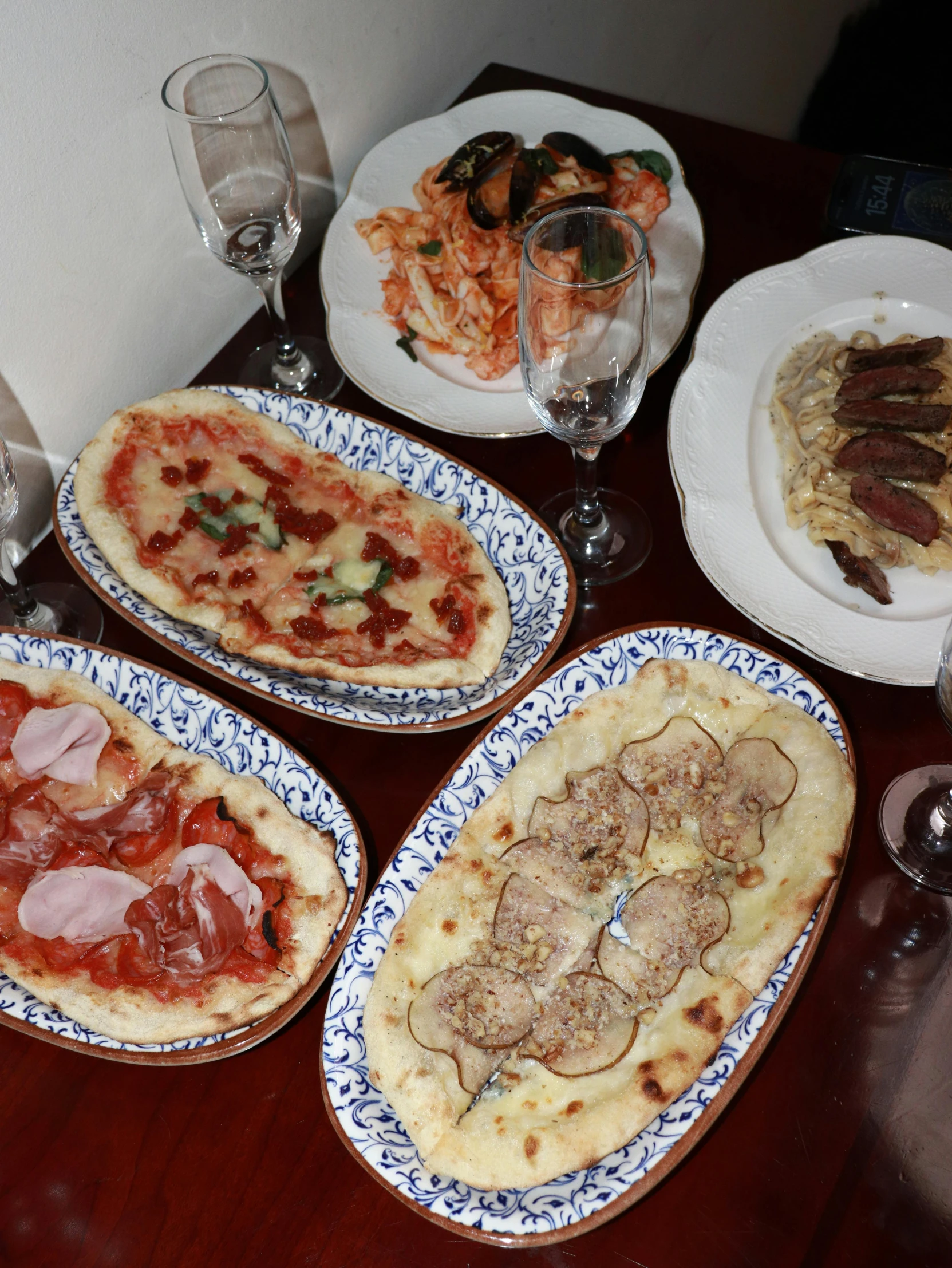 a wooden table topped with three large pizzas