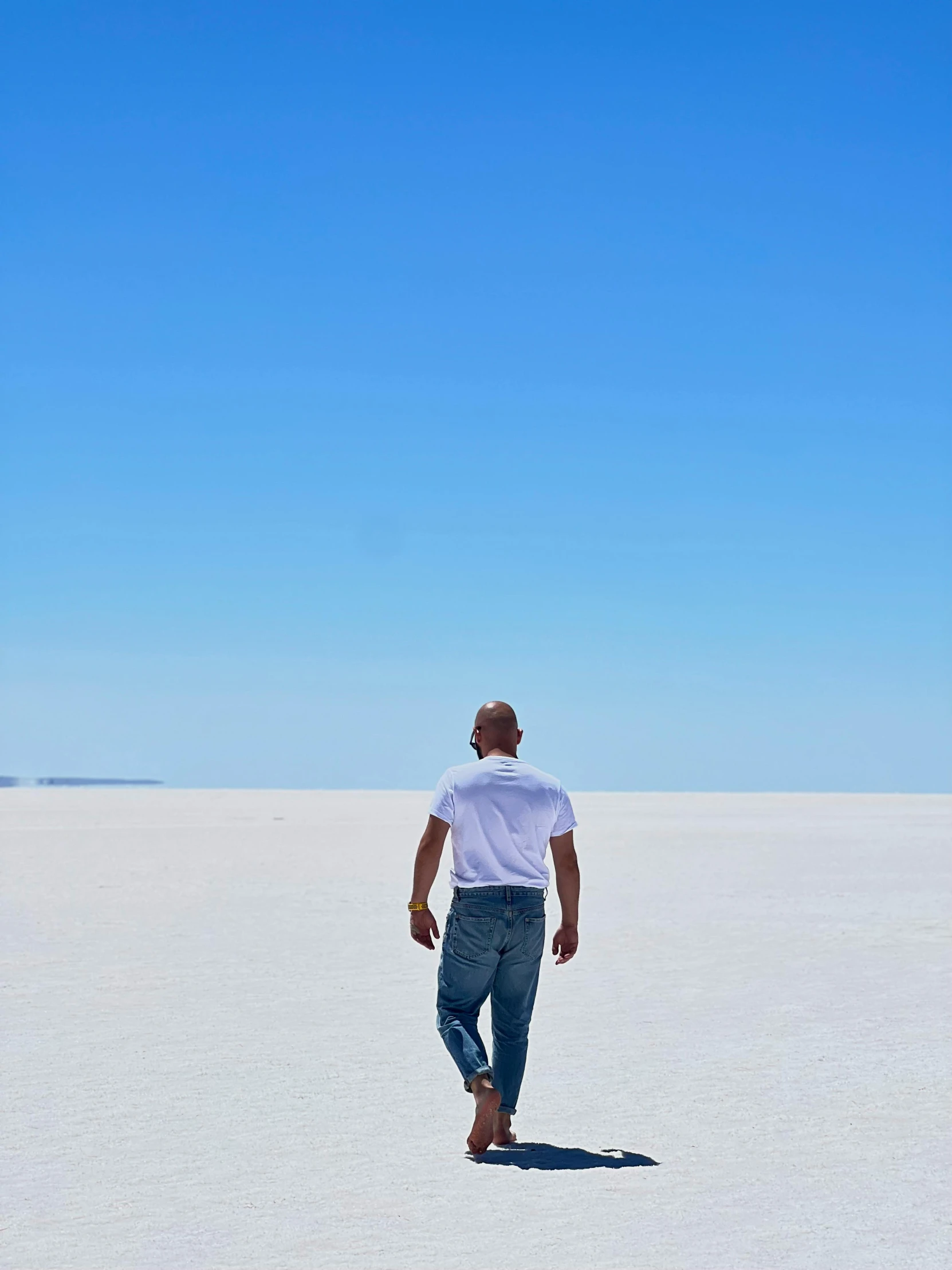 a man standing on a white sandy beach with a sky background