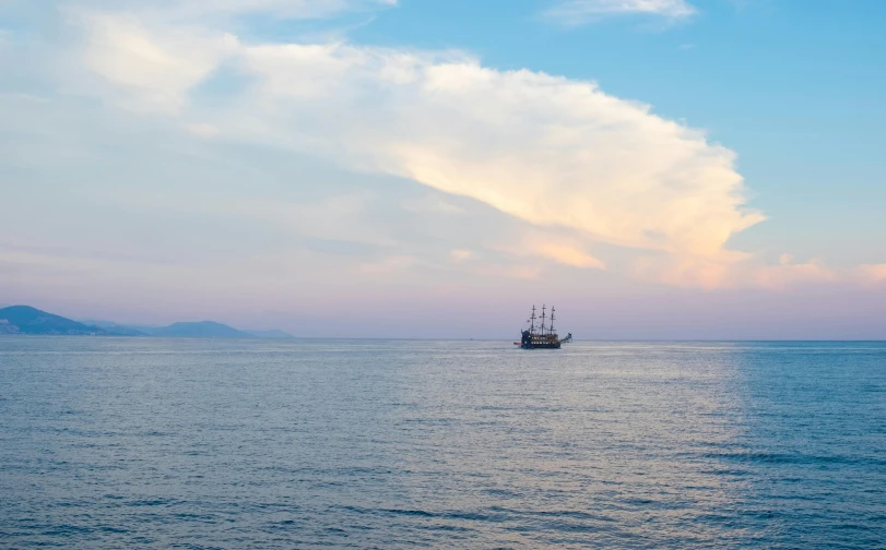 a ship on the water with a cloud in the background