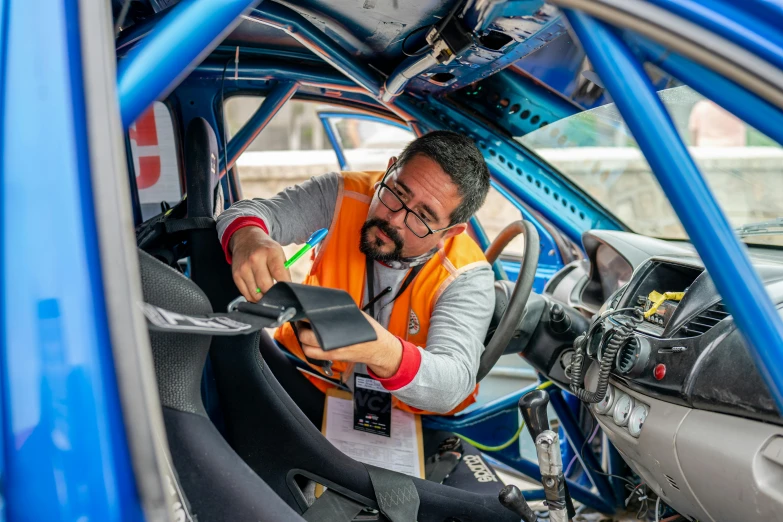 a man in an automobile is repairing his vehicle's seat